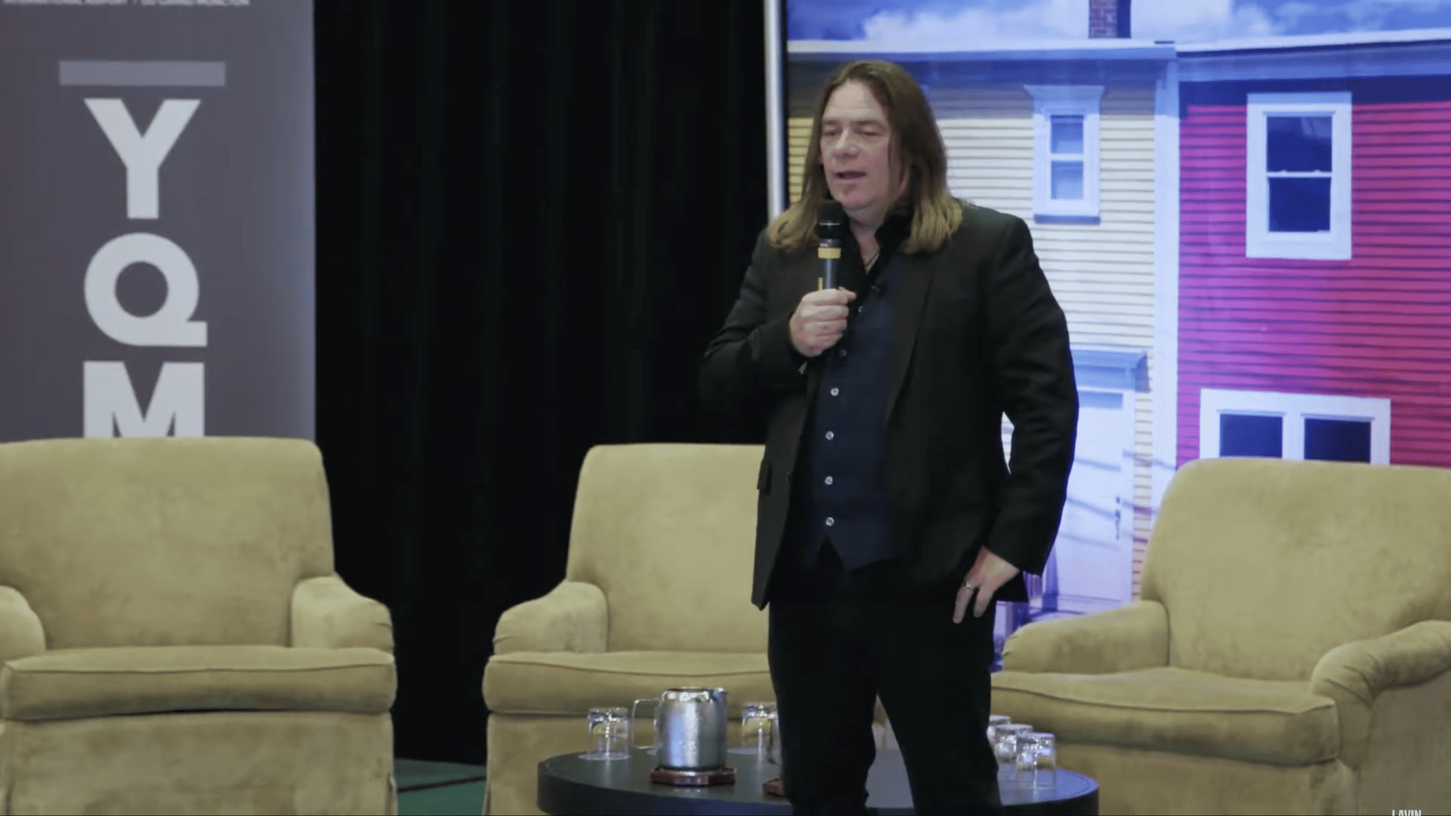 Alan Doyle, a light-skinned man with brown hair, giving a talk onstage.