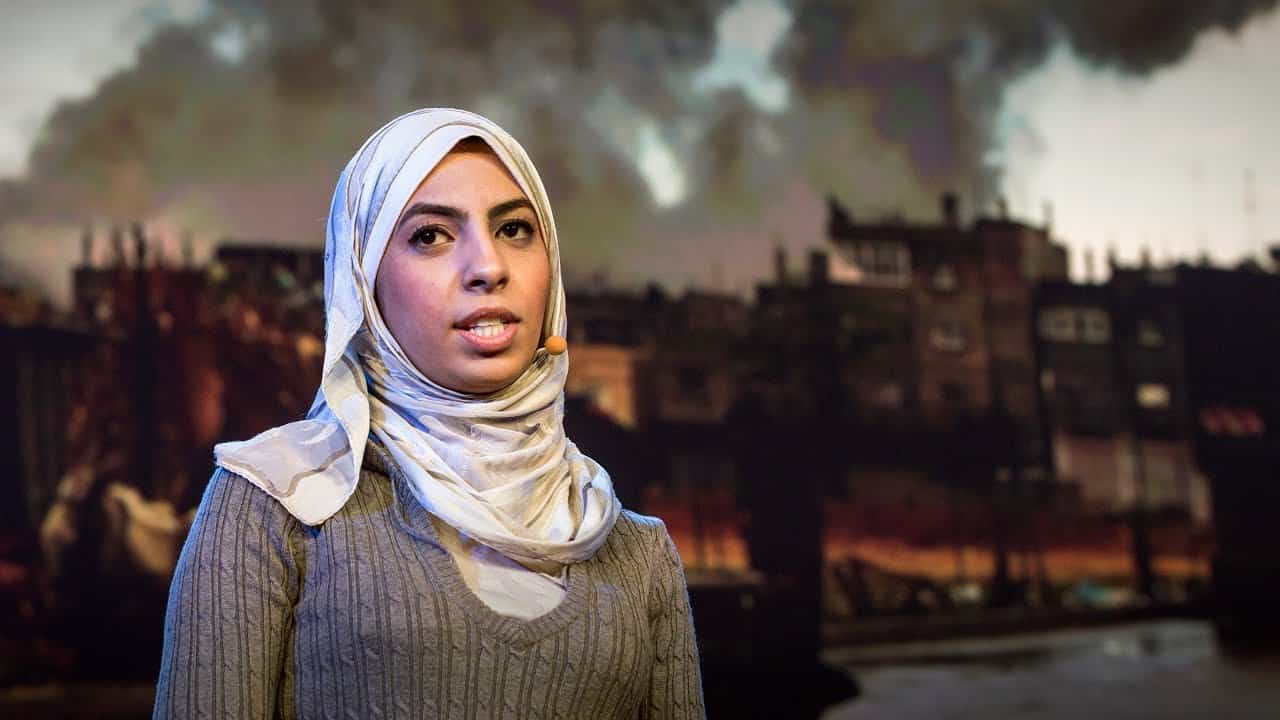 Eman Mohammed, a brown-skinned woman wearing a hijab, gives a talk onstage.
