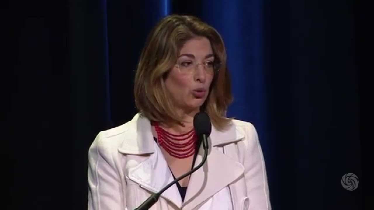 Naomi Klein, a light-skinned woman with brown hair, speaks at a podium.