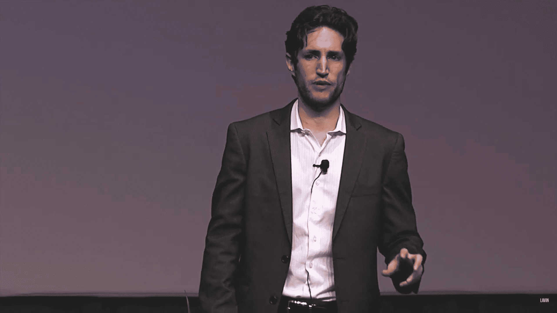 Adam Alter, a light-skinned man with dark hair, gives a talk onstage.