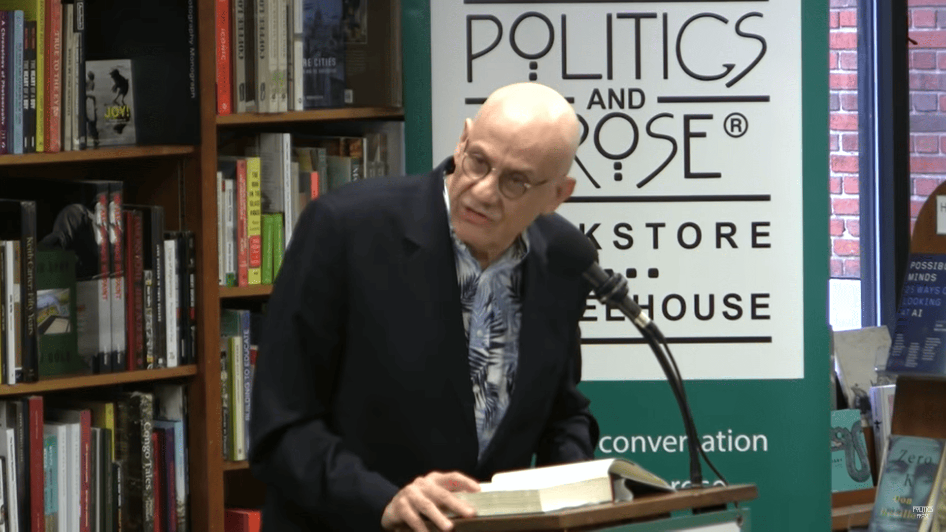 James Ellroy, a light-skinned man with glasses, giving a talk.